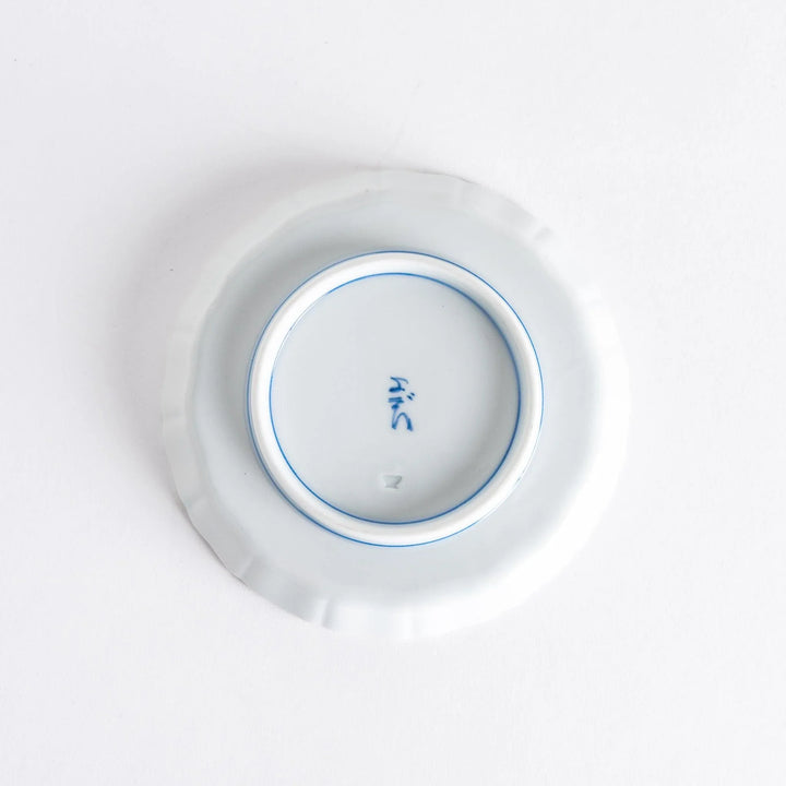 A small round plate with a traditional Japanese design depicting a landscape and floral elements.