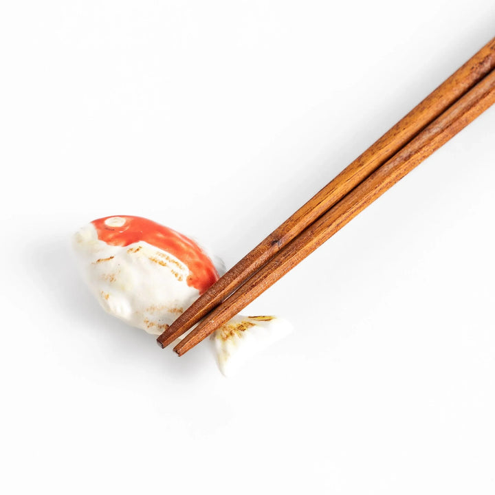 Chopstick rest shaped like a sea bream, intricately painted with red and white hues.