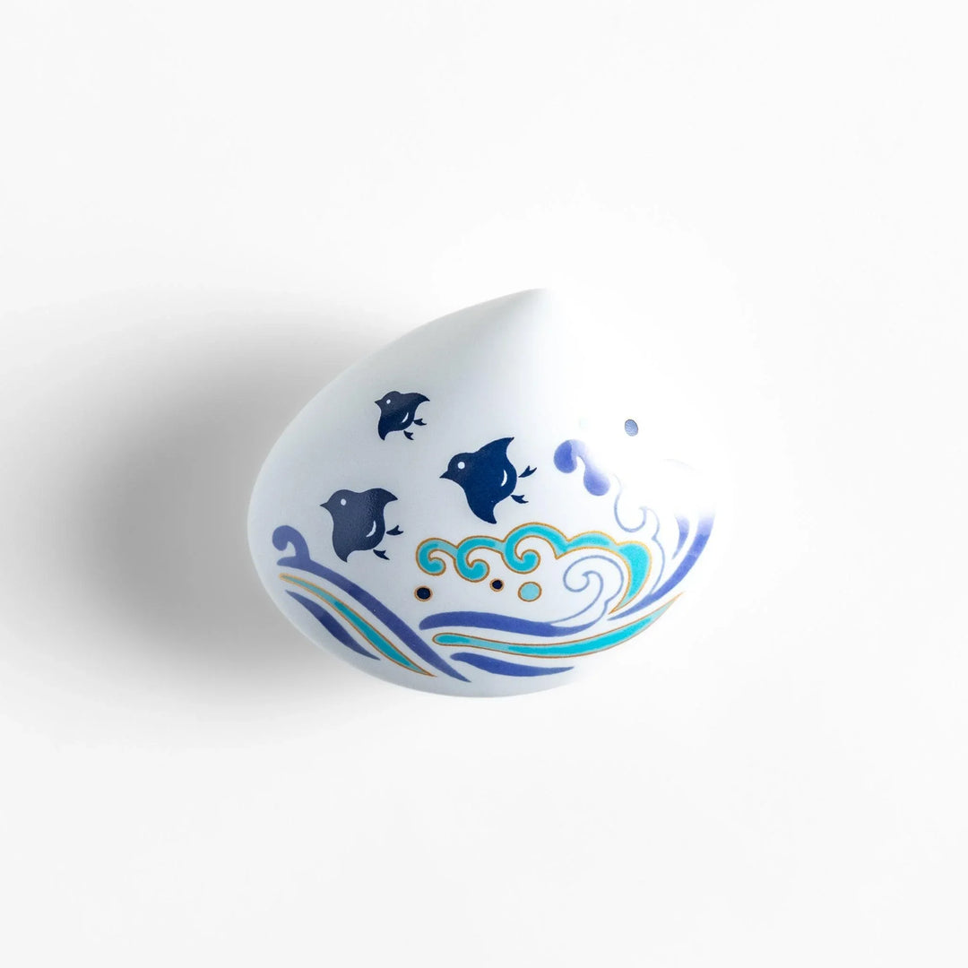 White seashell-shaped ceramic incense holder with blue wave and seabird motif and rounded holder for secure placement.