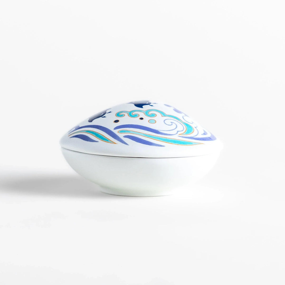 White seashell-shaped ceramic incense holder with blue wave and seabird motif and rounded holder for secure placement.