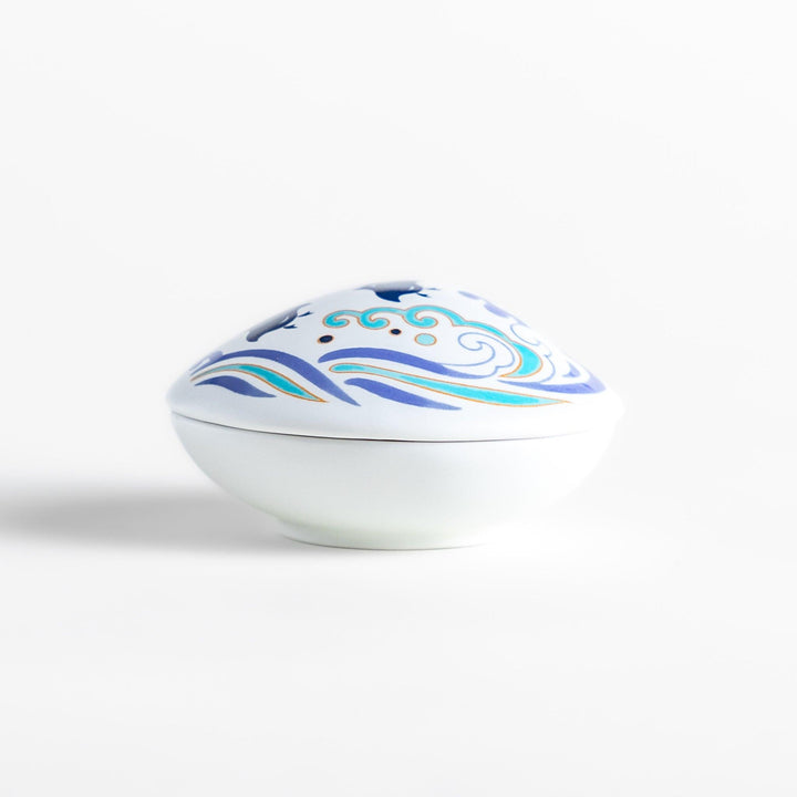 White seashell-shaped ceramic incense holder with blue wave and seabird motif and rounded holder for secure placement.