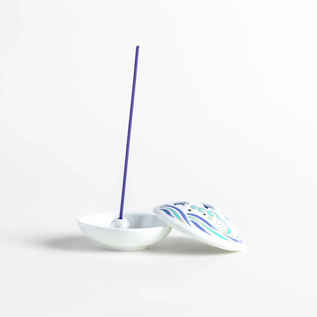 White seashell-shaped ceramic incense holder with blue wave and seabird motif and rounded holder for secure placement.