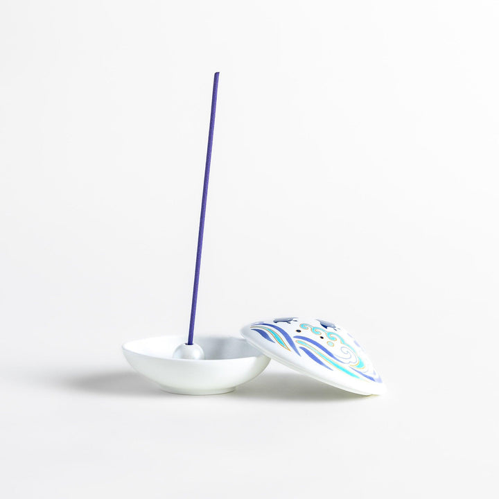 White seashell-shaped ceramic incense holder with blue wave and seabird motif and rounded holder for secure placement.