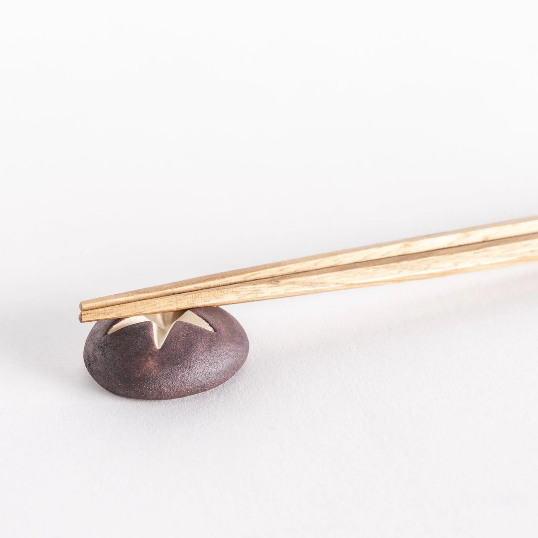 Close-up of chopsticks resting on the shiitake mushroom-shaped chopsticks rest.