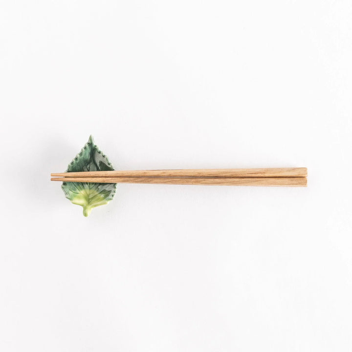 Full view of the shiso leaf chopsticks rest with chopsticks placed across its central ridge.