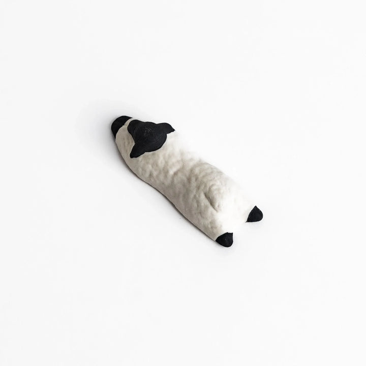Sleeping sheep chopstick rest in black and white, crafted with a minimalist design for a playful touch.