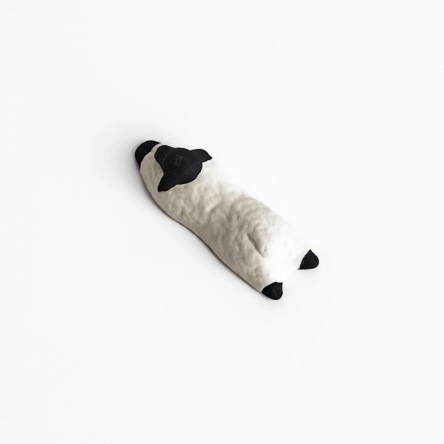 Sleeping sheep chopstick rest in black and white, crafted with a minimalist design for a playful touch.