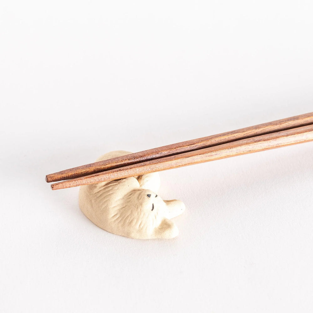 Sleepy cat ceramic chopstick rest with relaxed pose adding adorable accent to Japanese dining table.