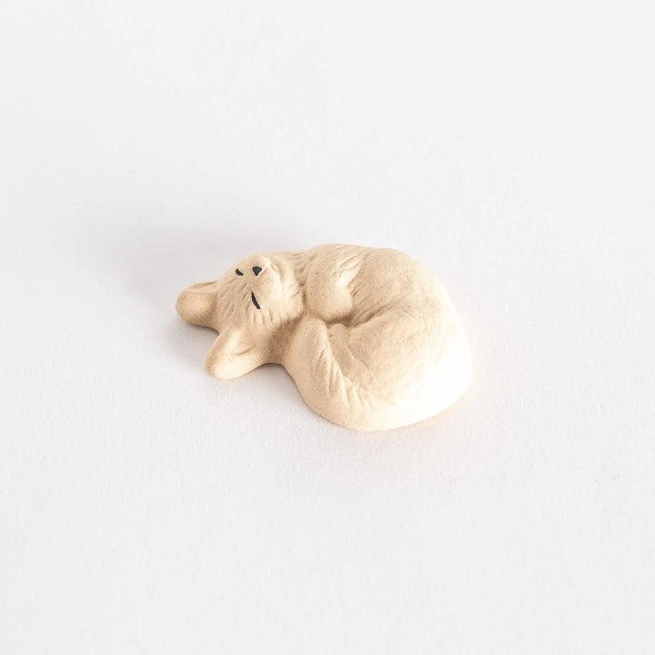 Angled view of a ceramic sleeping cat chopstick rest, highlighting its soft curves.