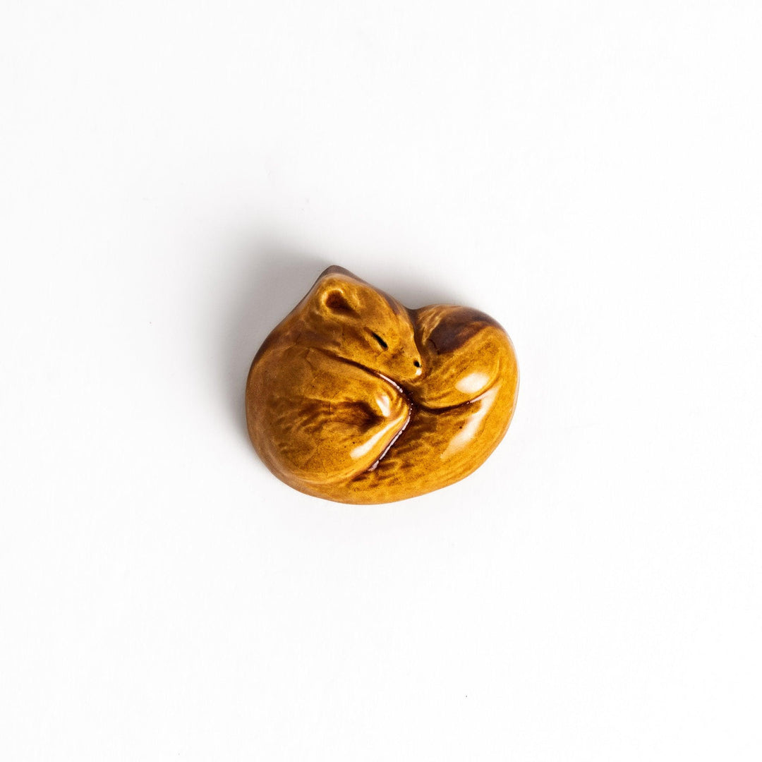 Brown ceramic squirrel chopstick rest in sleeping pose adding woodland charm to your dining table.