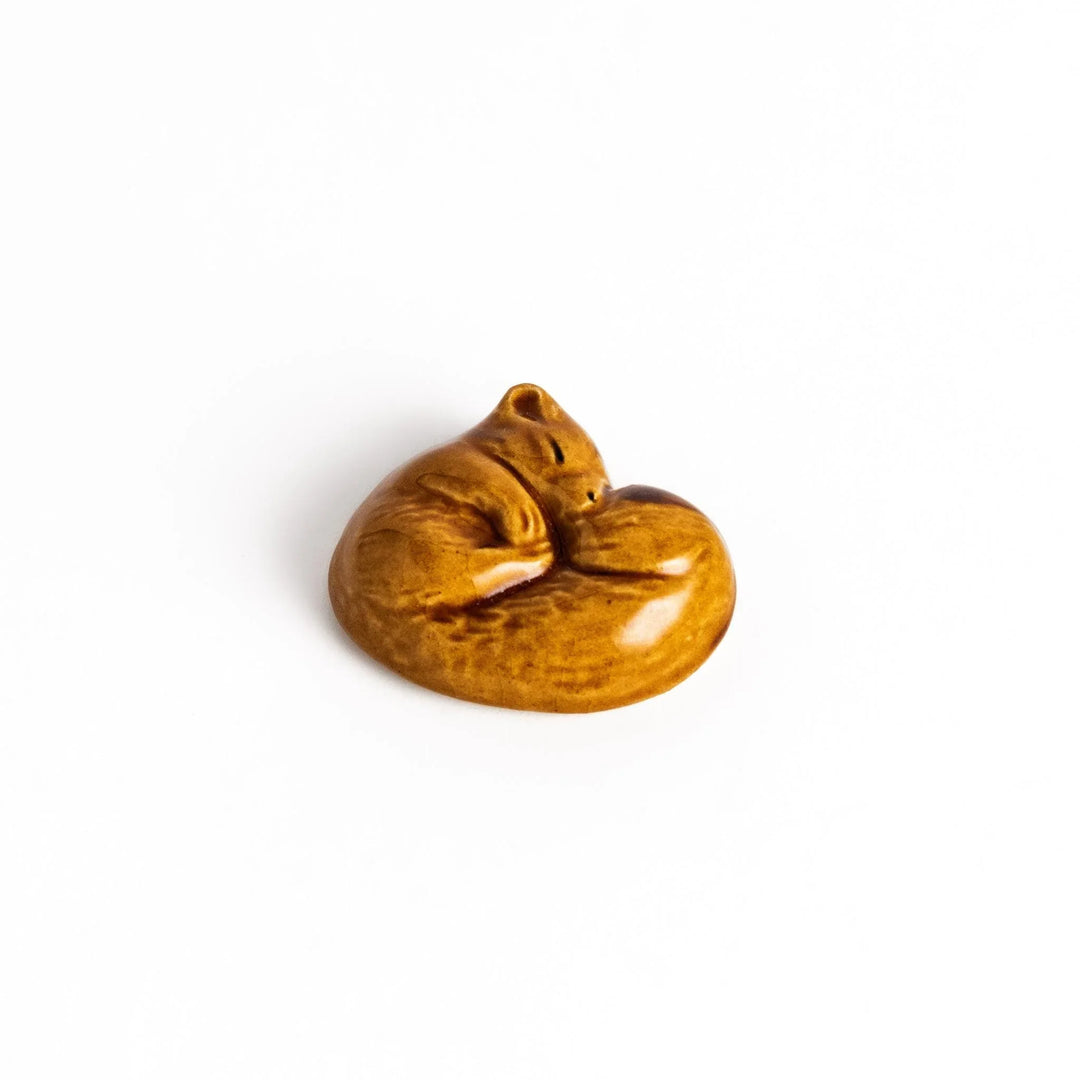 Brown ceramic squirrel chopstick rest in sleeping pose adding woodland charm to your dining table.