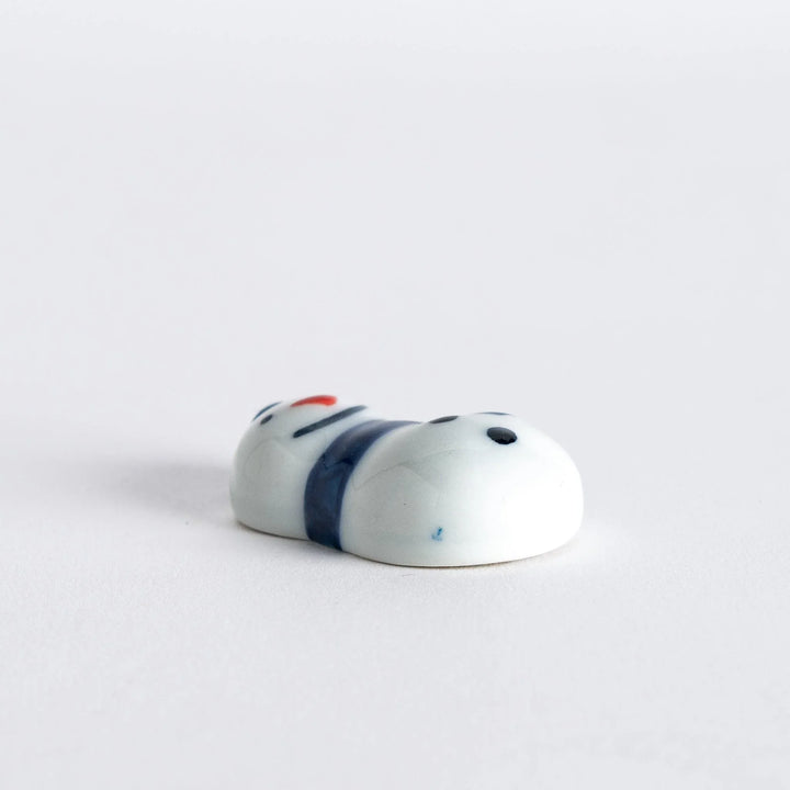 Snowman shaped ceramic chopstick rest with scarf detail adding cheerful winter charm to Japanese table setting.