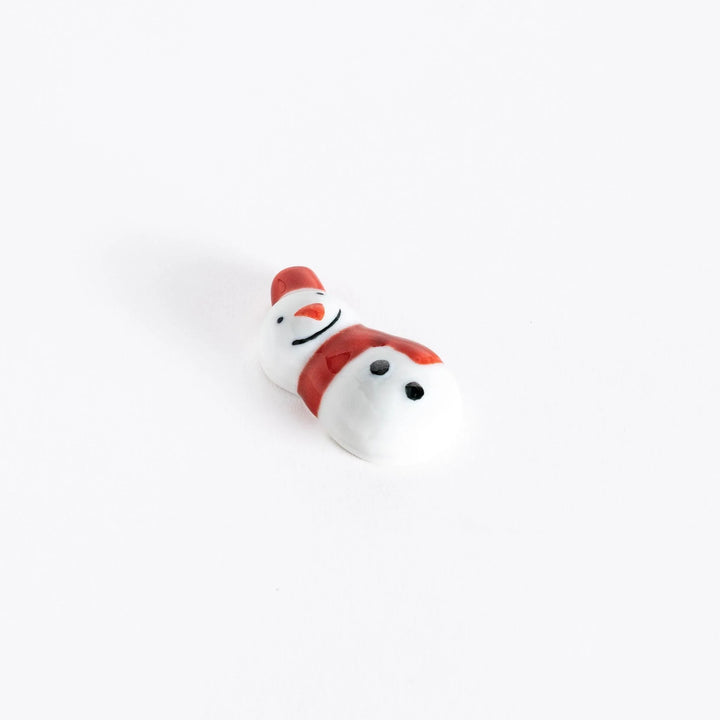 A slightly angled view of the red-scarfed snowman chopstick rest, emphasizing its round shape and charming expression.