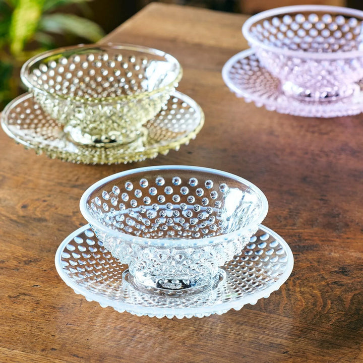 Glass dessert bowl and saucer available in pink, amber, and clear, each with raised dots and radiant base design.