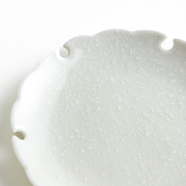 Ceramic sauce dishes with scalloped edges, available in black and white.