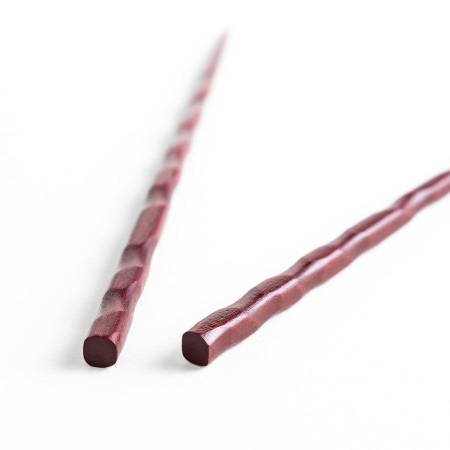 Lacquered chopsticks pair with carved textured surface for elegant grip available in black or red.
