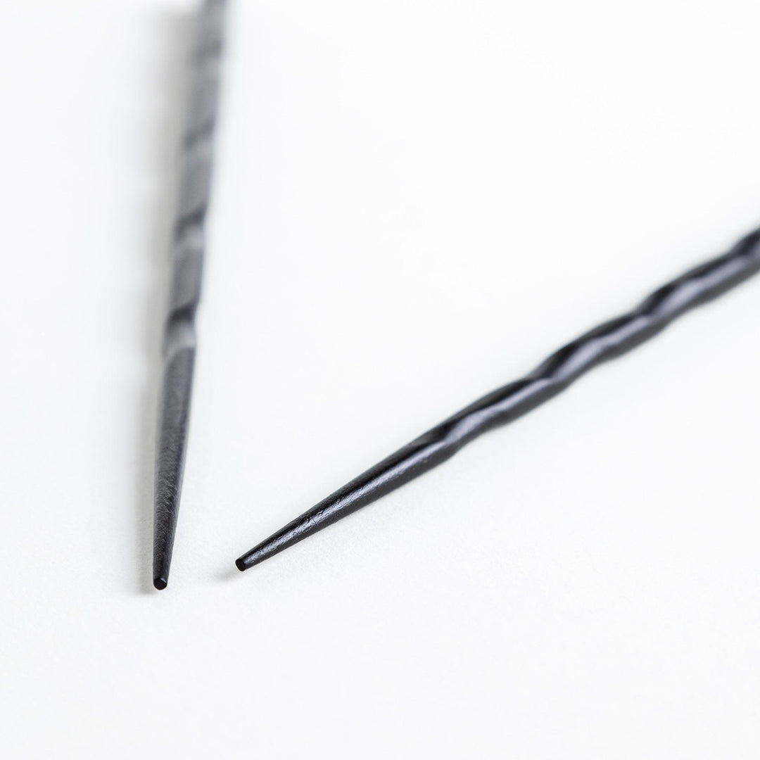 Lacquered chopsticks pair with carved textured surface for elegant grip available in black or red.