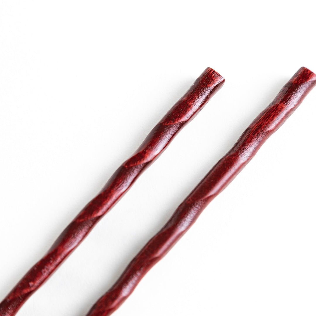 Lacquered chopsticks pair with carved textured surface for elegant grip available in black or red.
