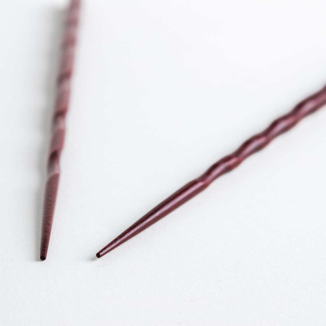 Lacquered chopsticks pair with carved textured surface for elegant grip available in black or red.
