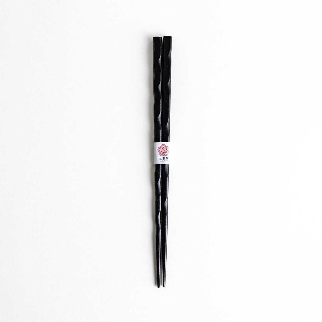Lacquered chopsticks pair with carved textured surface for elegant grip available in black or red.