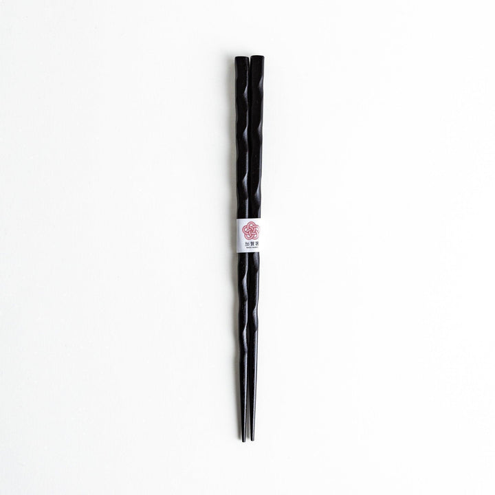 Lacquered chopsticks pair with carved textured surface for elegant grip available in black or red.