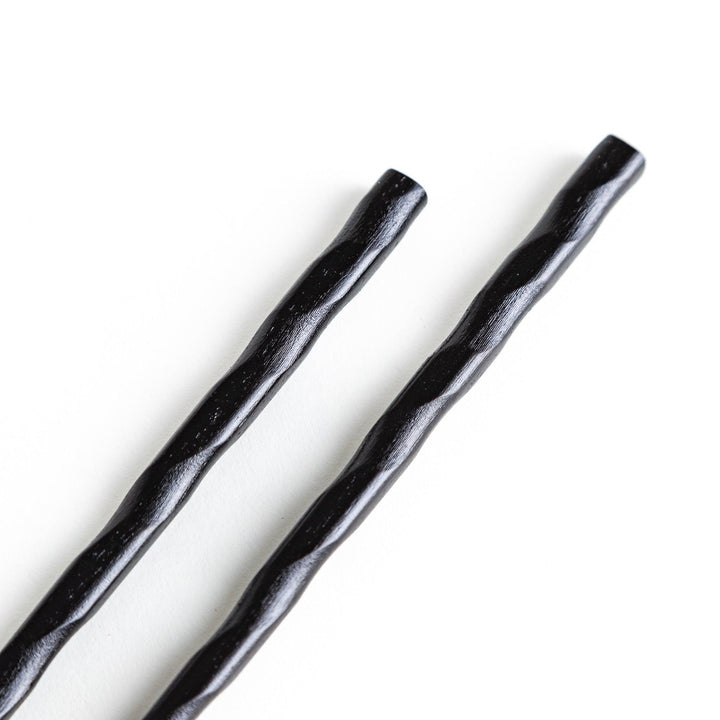Lacquered chopsticks pair with carved textured surface for elegant grip available in black or red.