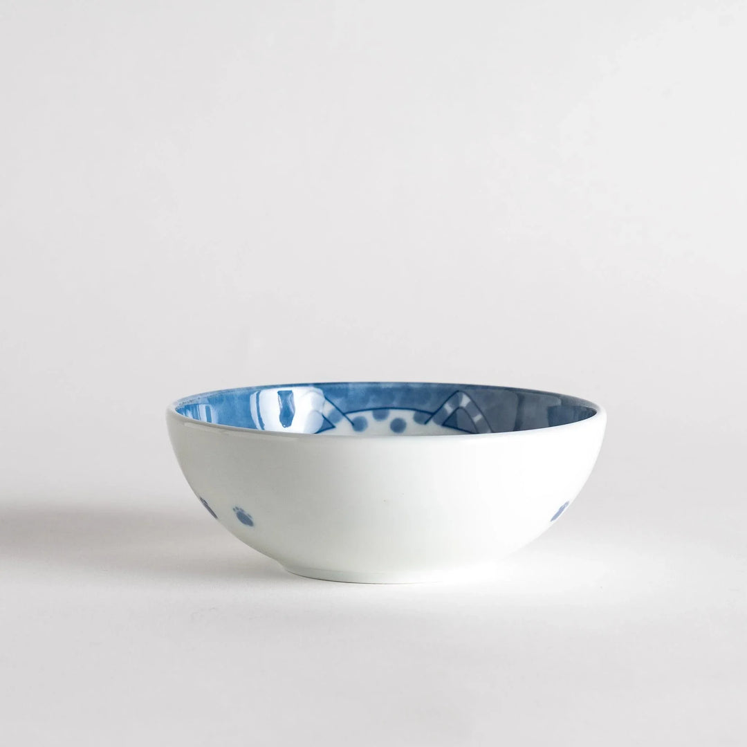 A dessert bowl with a chubby blue-spotted cat, looking peaceful and content.