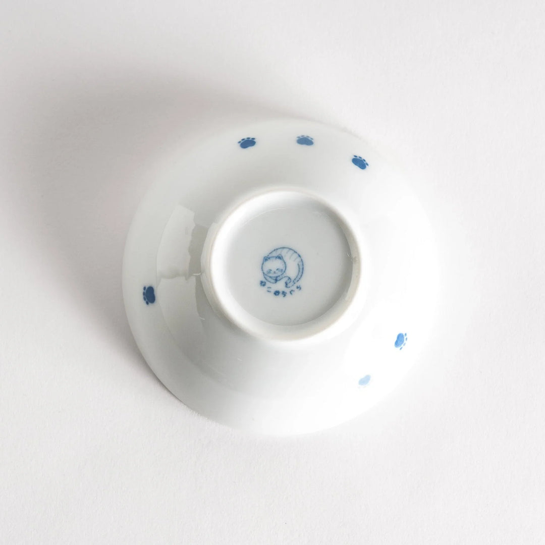 A dessert bowl with a chubby blue-spotted cat, looking peaceful and content.