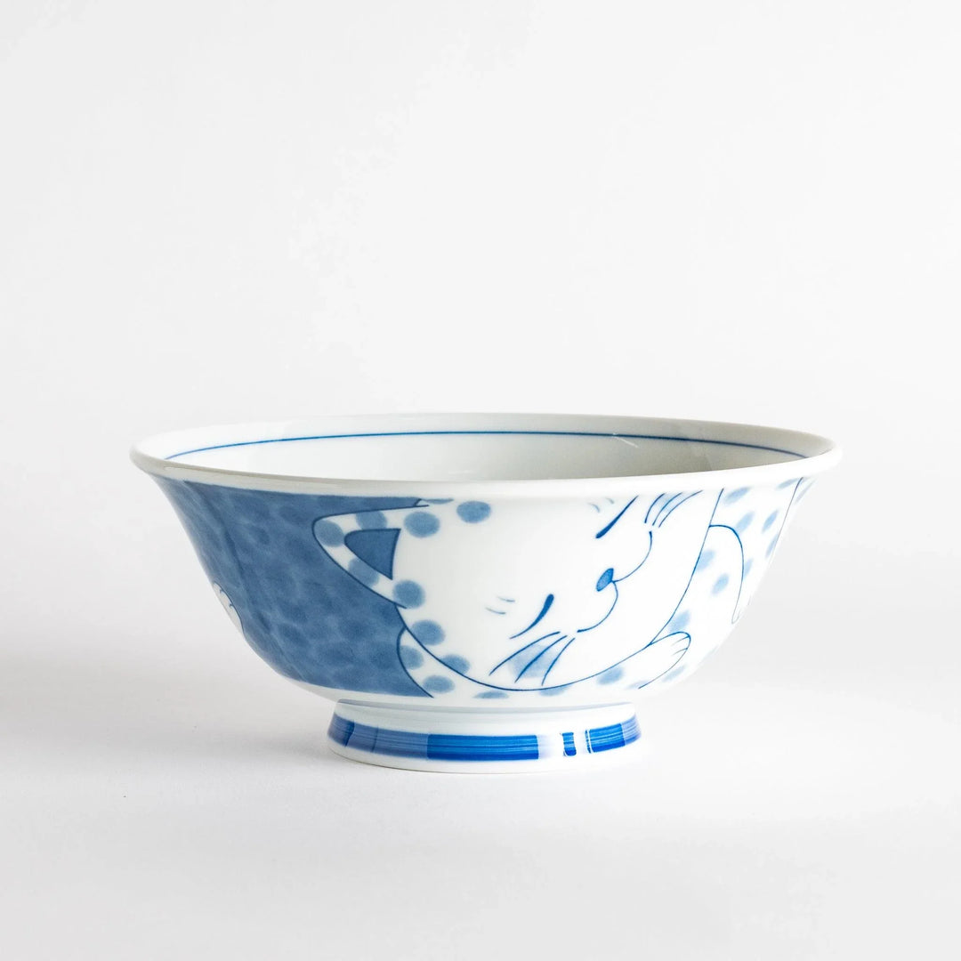 A ramen bowl with a design of a blue and white spotted cat, appearing cozy and content.