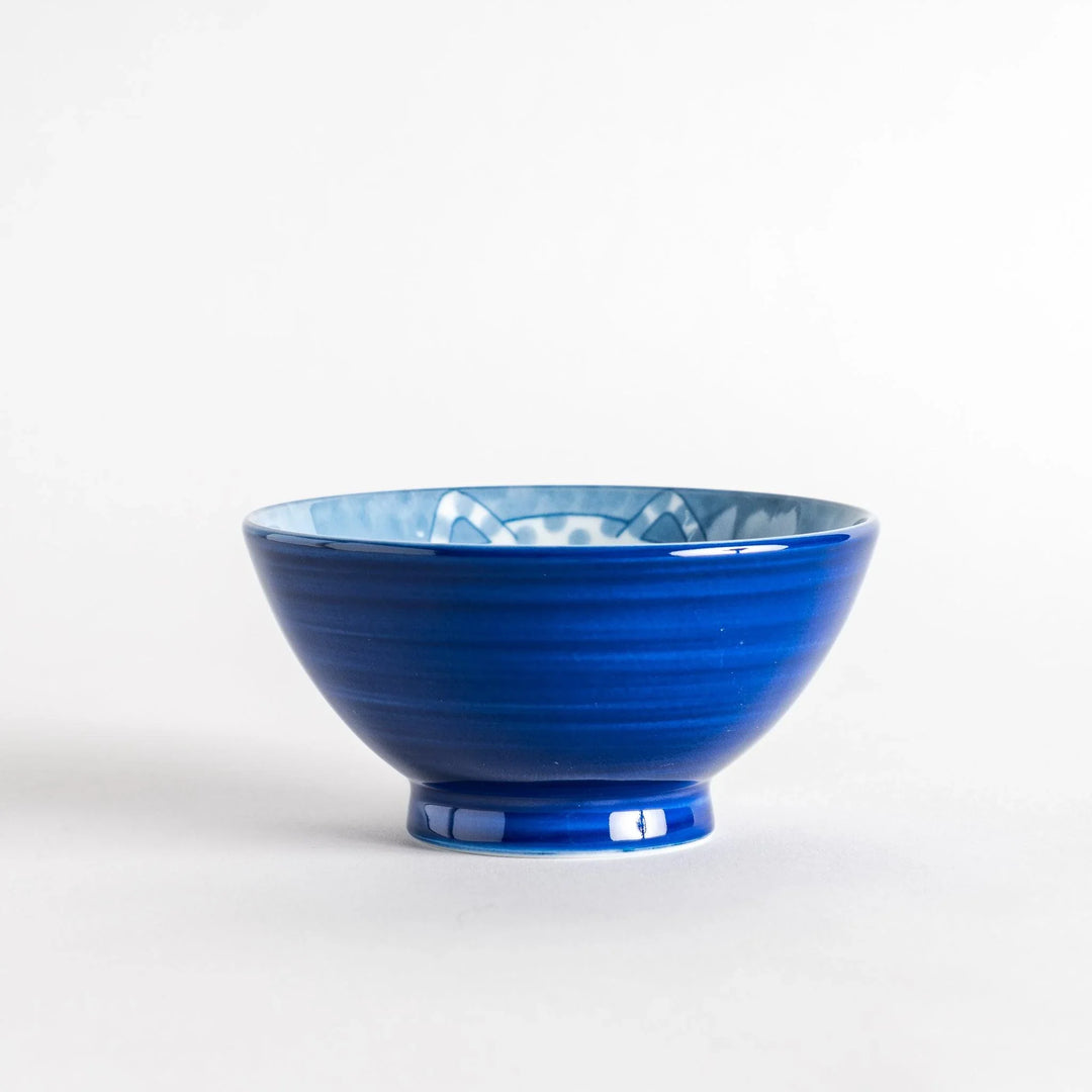 A rice bowl featuring a chubby blue-spotted white cat, sitting contentedly.