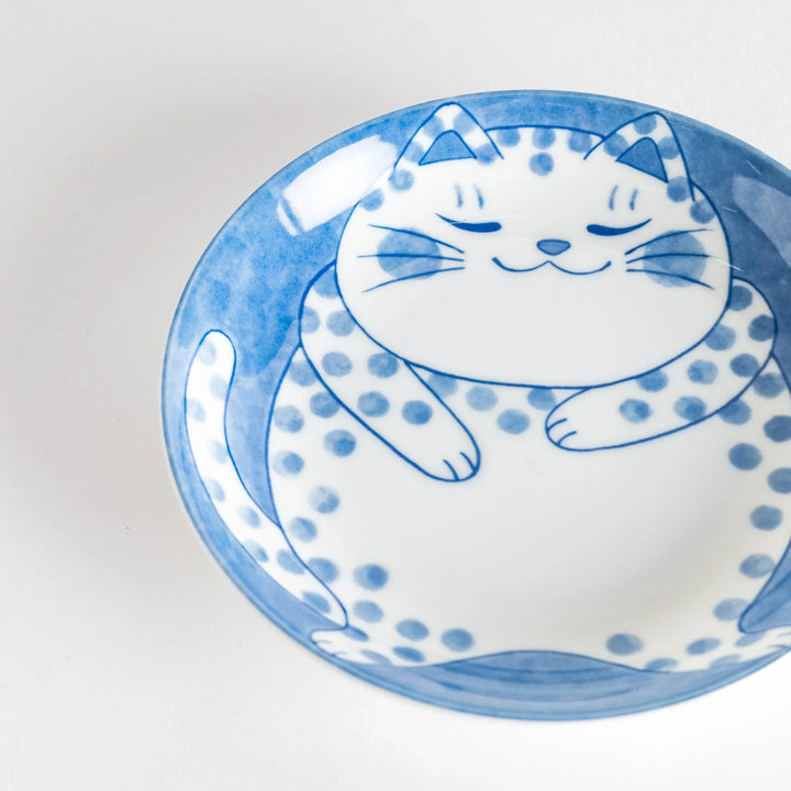 A salad plate featuring a chubby blue-spotted white cat with a contented expression.
