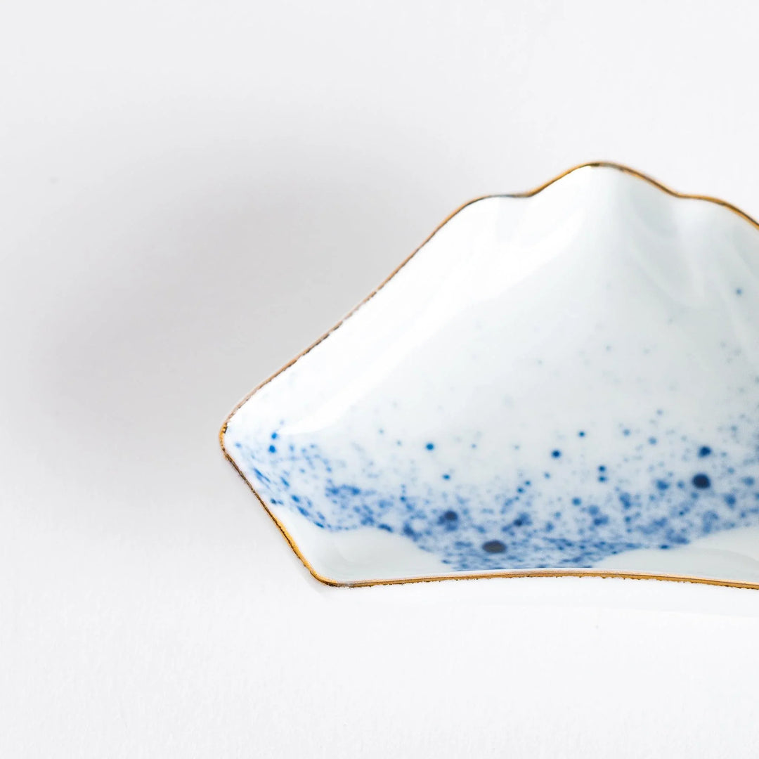Mount Fuji shaped mini Japanese sauce dish with blue ink pattern filled with soy sauce beside sashimi set.