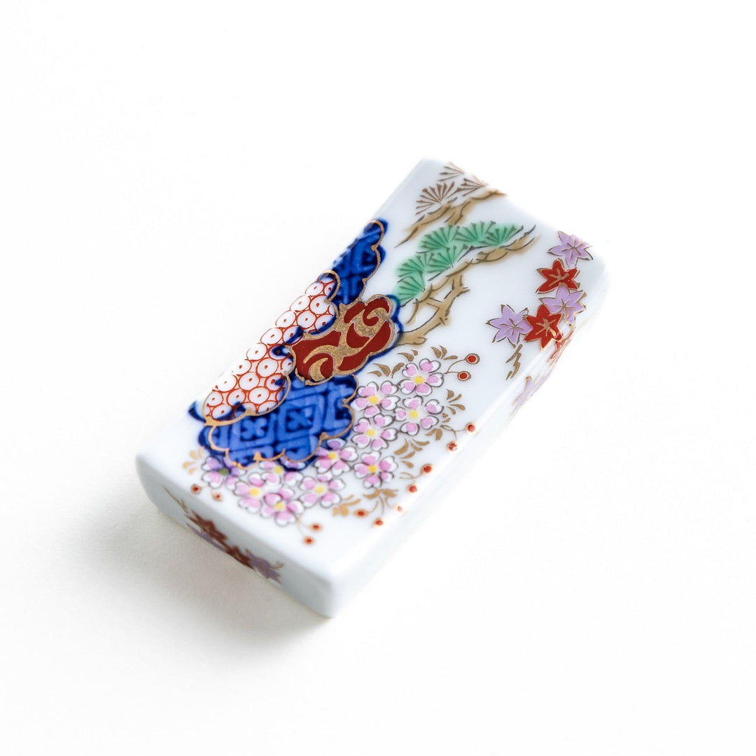 Rectangular ceramic chopstick rest with blue red and green Japanese patterns for decorative table setting.