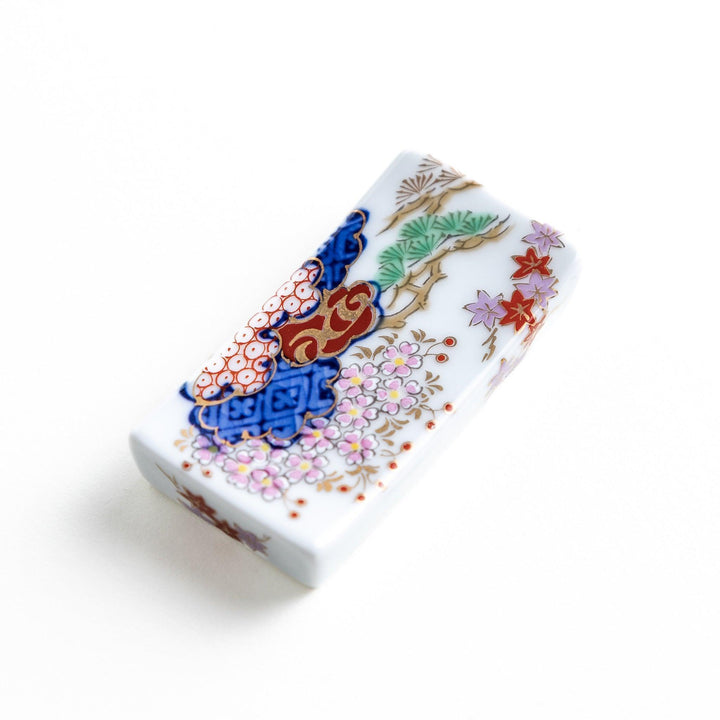 Rectangular ceramic chopstick rest with blue red and green Japanese patterns for decorative table setting.