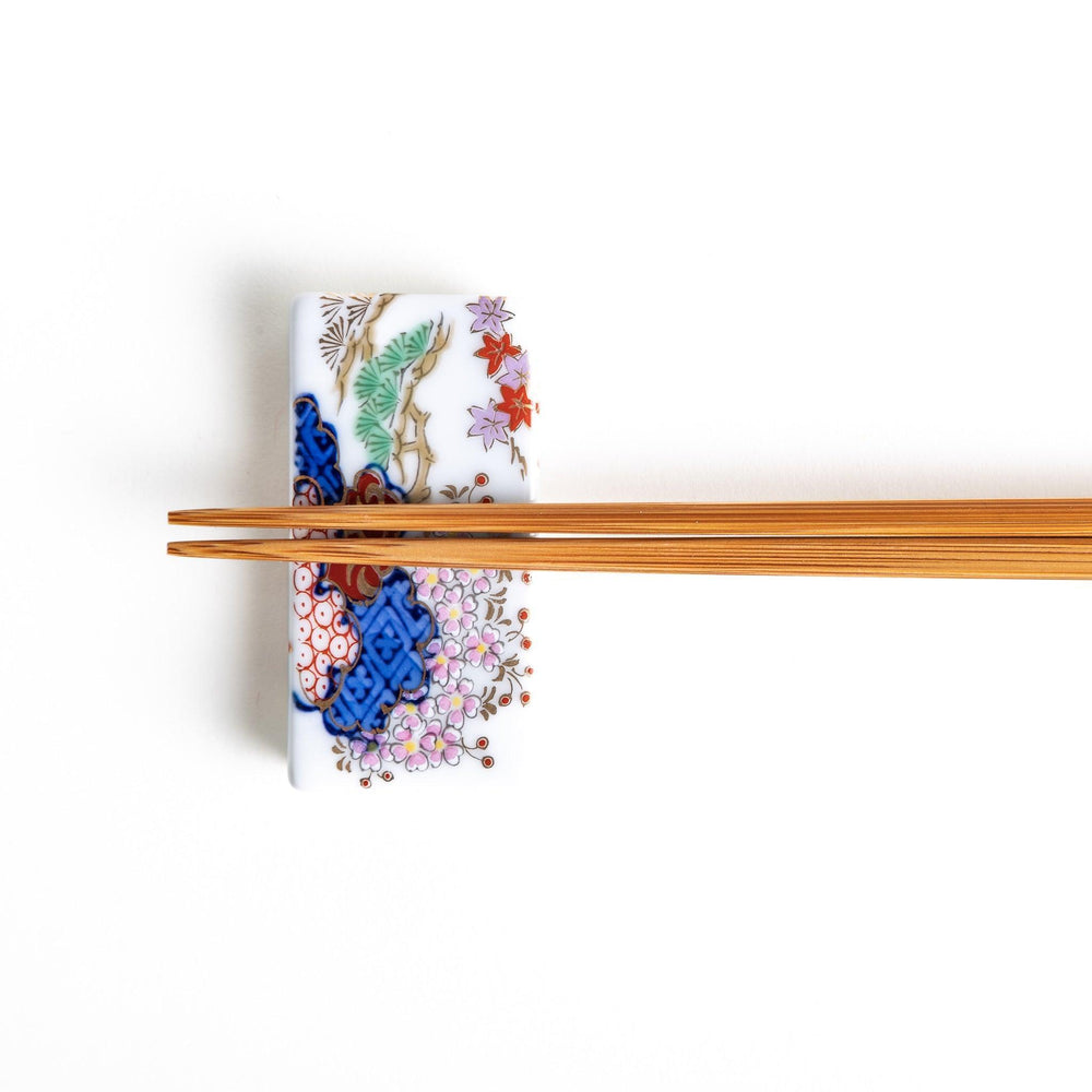 Rectangular ceramic chopstick rest with blue red and green Japanese patterns for decorative table setting.
