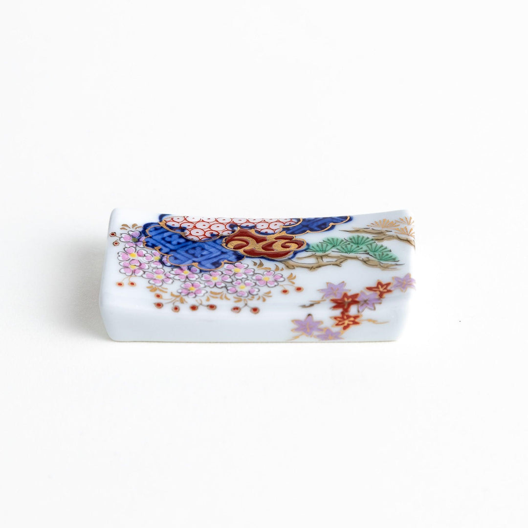Rectangular ceramic chopstick rest with blue red and green Japanese patterns for decorative table setting.