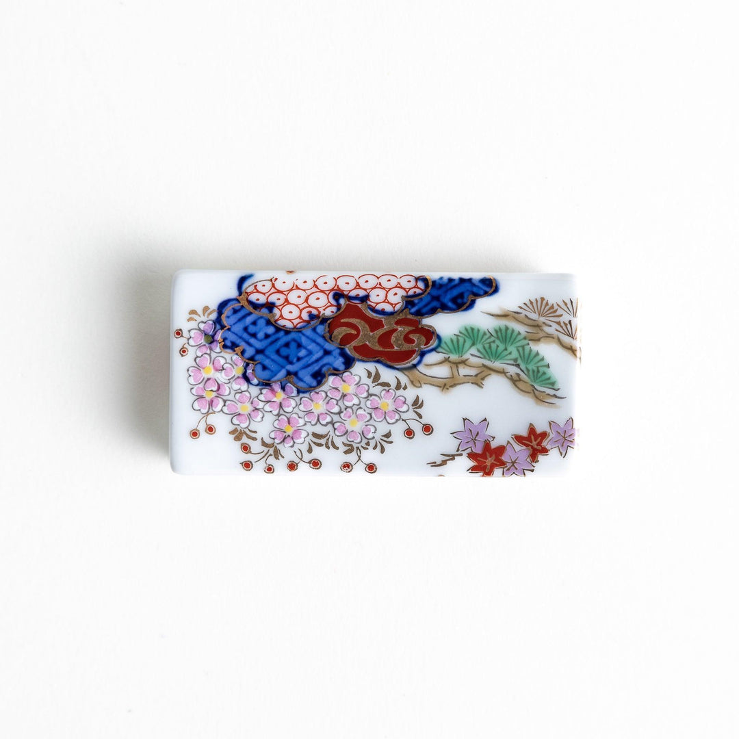 Rectangular ceramic chopstick rest with blue red and green Japanese patterns for decorative table setting.
