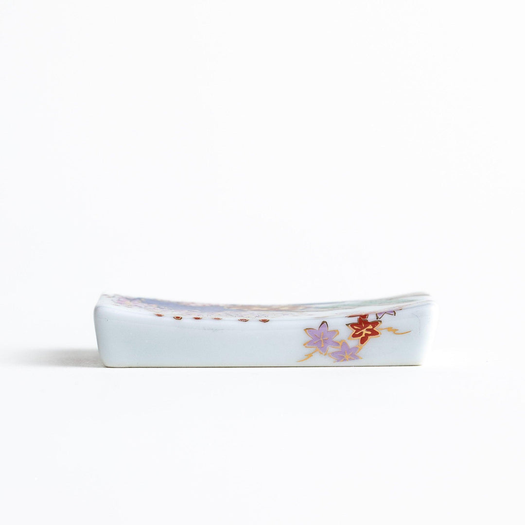 Rectangular ceramic chopstick rest with blue red and green Japanese patterns for decorative table setting.