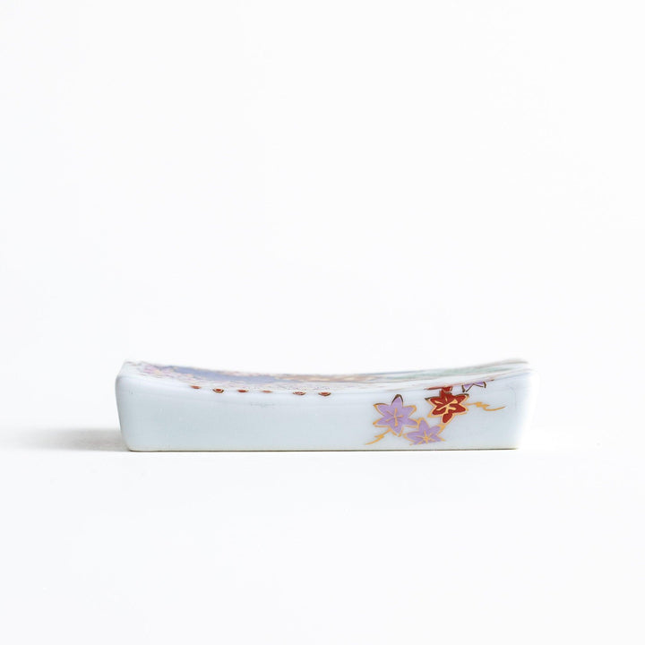 Rectangular ceramic chopstick rest with blue red and green Japanese patterns for decorative table setting.