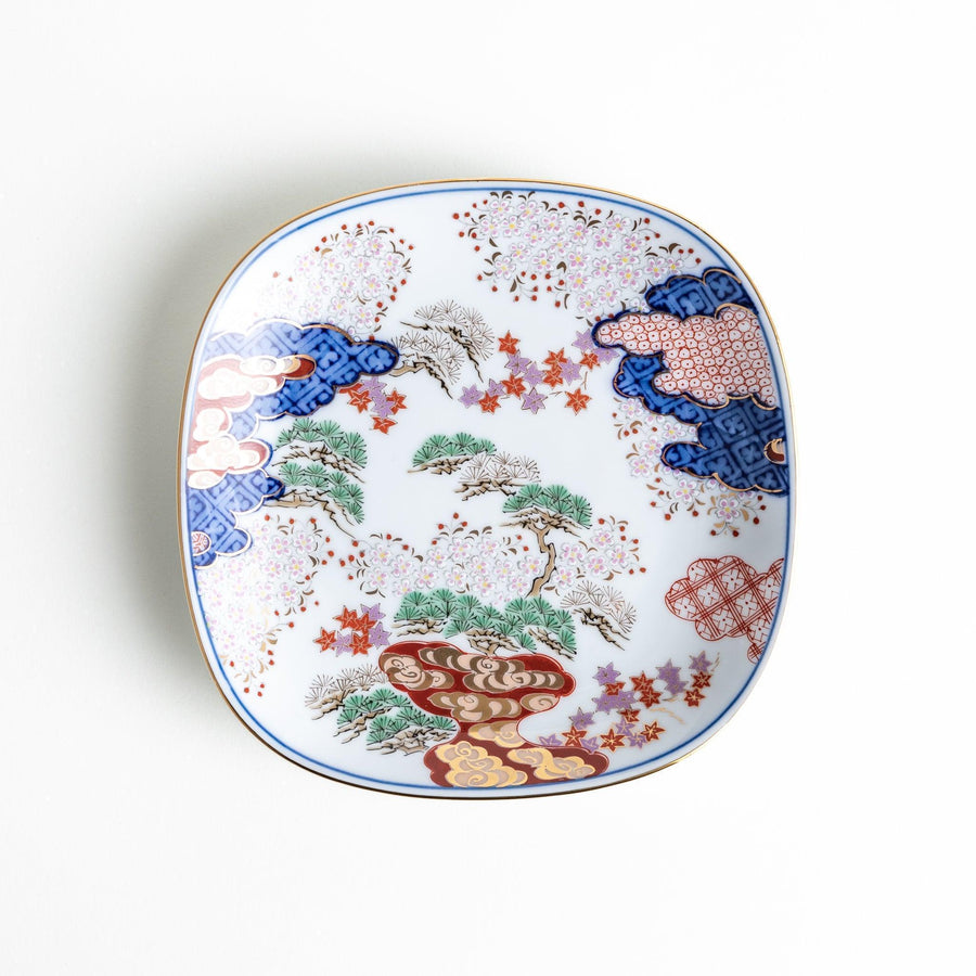 Square dessert plate with Japanese landscape design of trees and clouds bordered by red and blue patterns.
