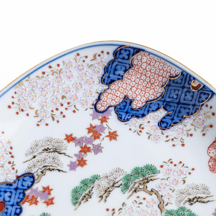 Square dessert plate with Japanese landscape design of trees and clouds bordered by red and blue patterns.