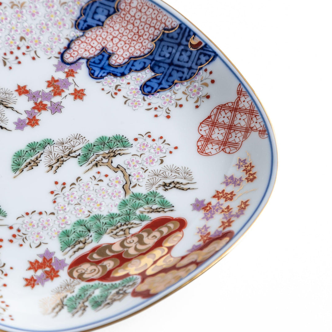 Square dessert plate with Japanese landscape design of trees and clouds bordered by red and blue patterns.