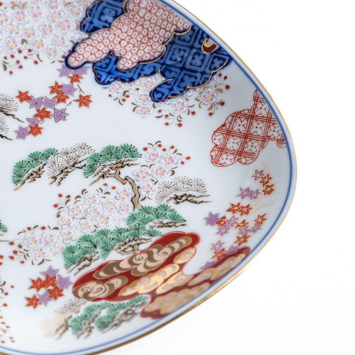 Square dessert plate with Japanese landscape design of trees and clouds bordered by red and blue patterns.