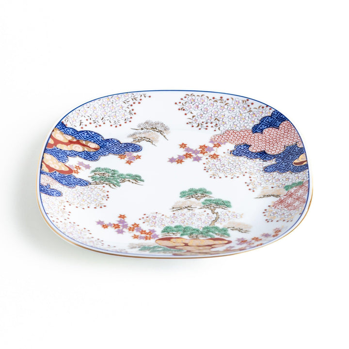 Square salad plate with Japanese landscape of trees clouds and maple leaves framed by blue red patterns.