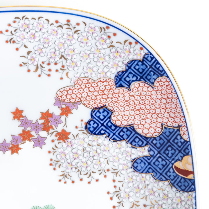Square salad plate with Japanese landscape of trees clouds and maple leaves framed by blue red patterns.