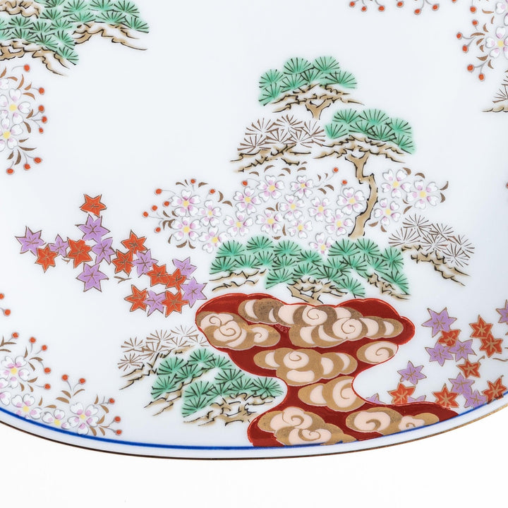 Square salad plate with Japanese landscape of trees clouds and maple leaves framed by blue red patterns.