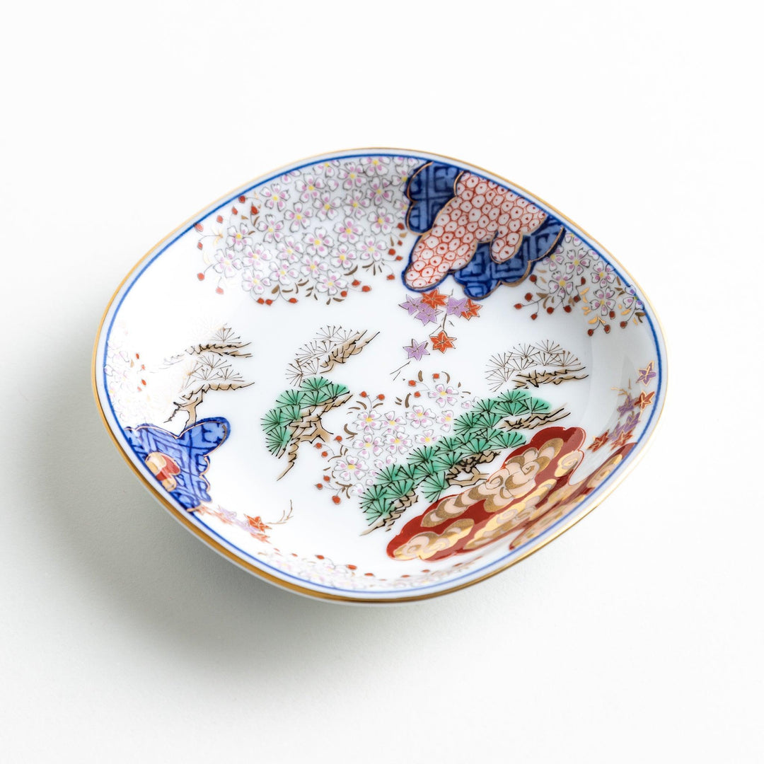 Square Japanese sauce dish with landscape trees clouds and golden sun bordered by blue and red patterns.
