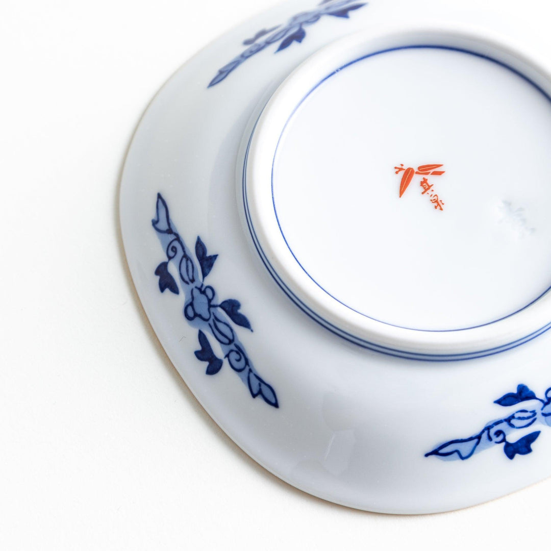 Square Japanese sauce dish with landscape trees clouds and golden sun bordered by blue and red patterns.