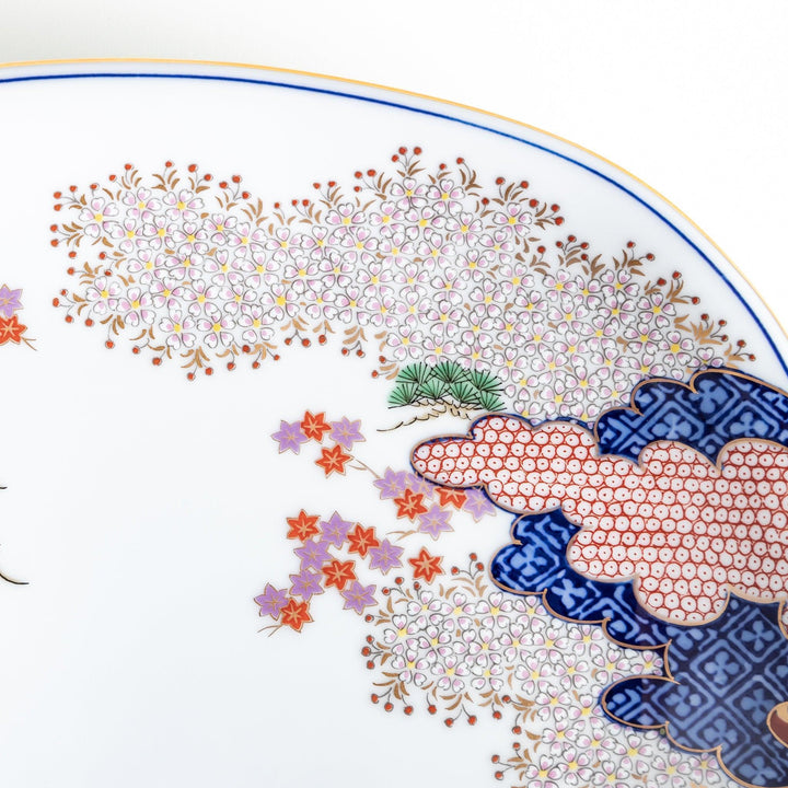 Square serving plate with white base featuring Japanese landscape of trees clouds and red maple leaves.