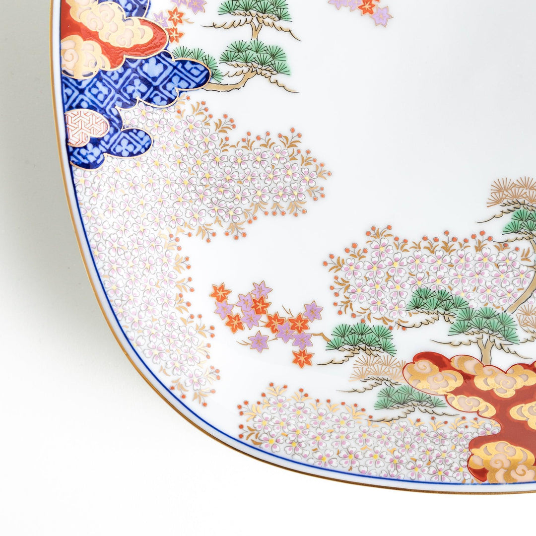 Square serving plate with white base featuring Japanese landscape of trees clouds and red maple leaves.